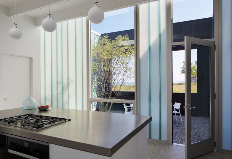 The kitchen is done with pendant lamps, cool views and sleek white cabinets, everywhere there's acess to outdoors The kitchen is done with pendant lamps, cool views and sleek white cabinets, everywhere there's acess to outdoors