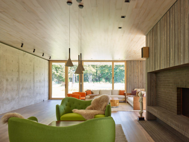 The living room is done with a large fireplace clad with brick and wood and a couple of bold green sofas