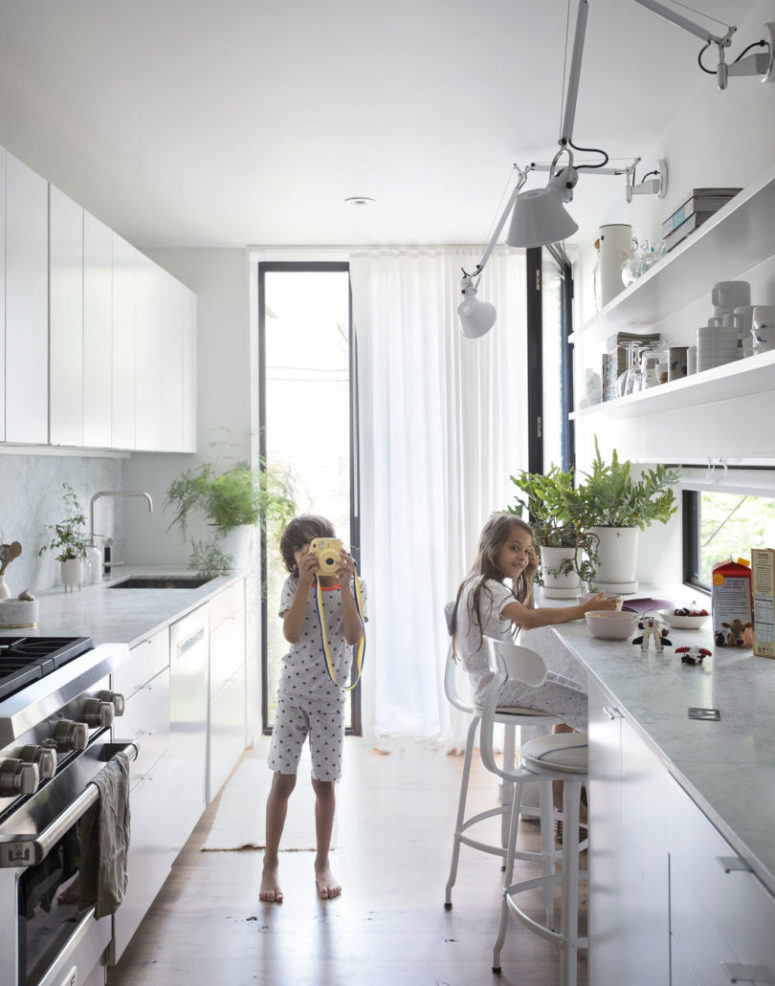 The kitchen is done with a tall narrow window, a window backsplash and comfy cabinets