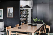 The dining space is done with a wooden table and chairs with black leather plus a black glass vase and a black pendant lamp
