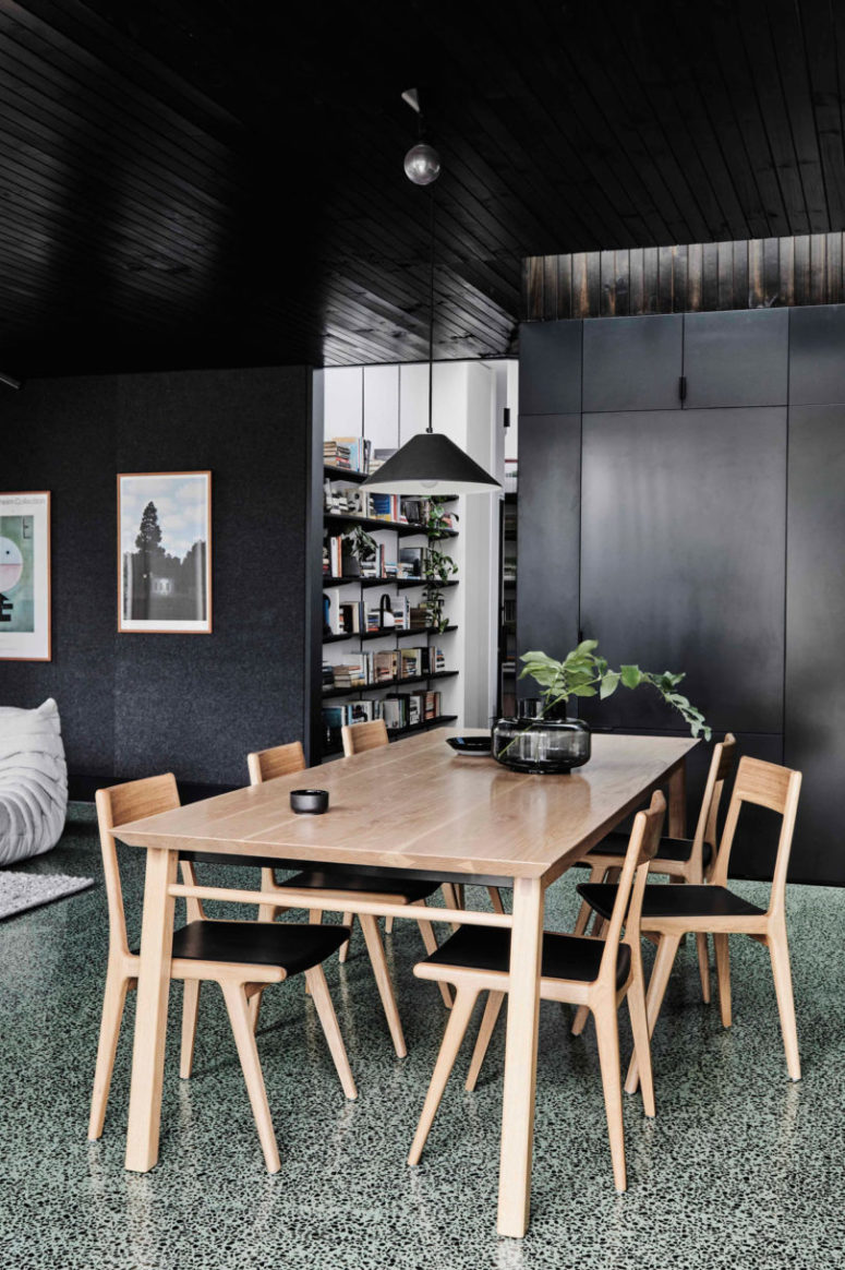 The dining space is done with a wooden table and chairs with black leather plus a black glass vase and a black pendant lamp The dining space is done with a wooden table and chairs with black leather plus a black glass vase and a black pendant lamp