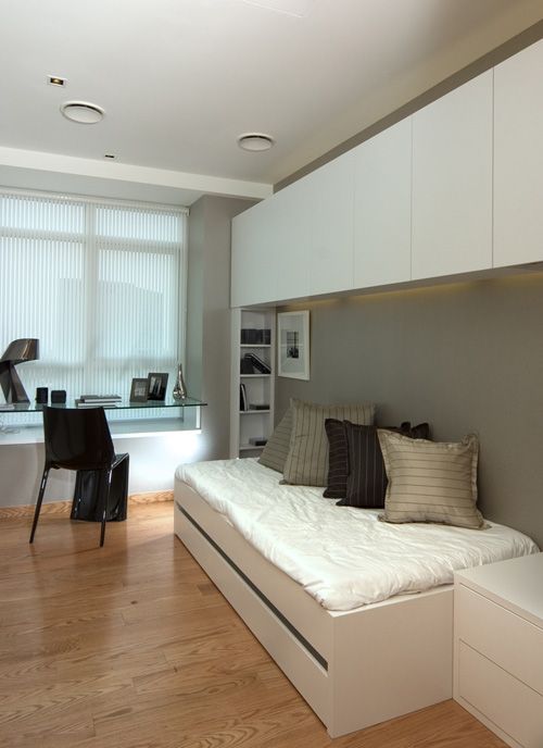 a small contemporary bedroom with a sleeping space, cabinets for storage and a glass windowsill