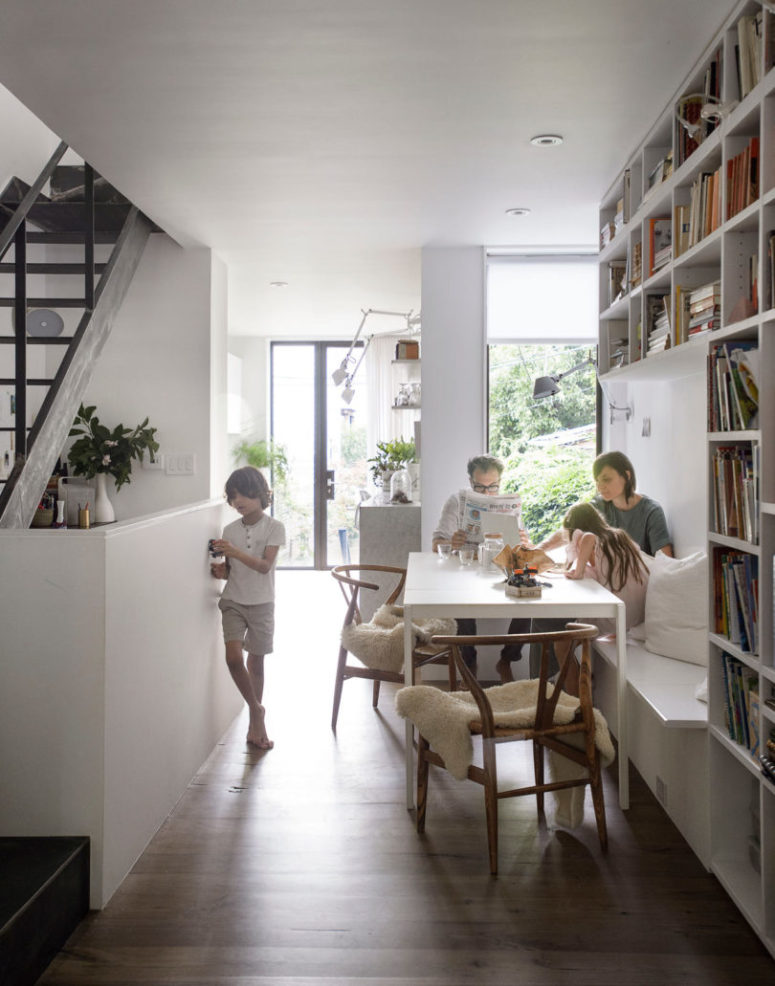 The dining space is done with a beanch with storage, shelves over it, wooden chairs and a dining table