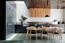 07 The kitchen features sleek black cabinets, upper light-colored wooden ones and some potted greenery