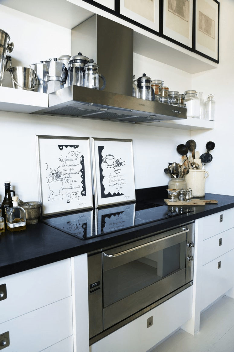 The kitchen is done with white cabinets and black countertops plus again art