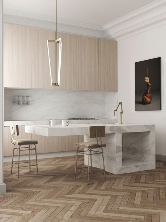a bright minimalist kitchen done in camel with white marble and brass touches
