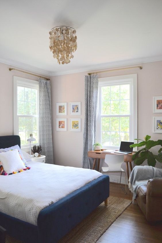 a cozy and wlecoming guest bedroom features a small desk by the window and a modern chair