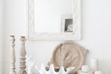 07 a whitewashed Indian console with wooden candle holders, a large shell and some decor of smaller shells