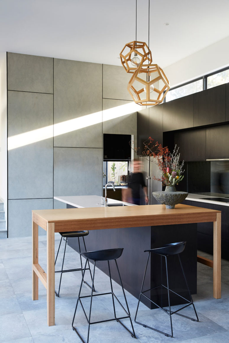 kitchen with a console table The kitchen is done with sleek grey and black cabinets, a wooden console table for having a meal and a kitchen island