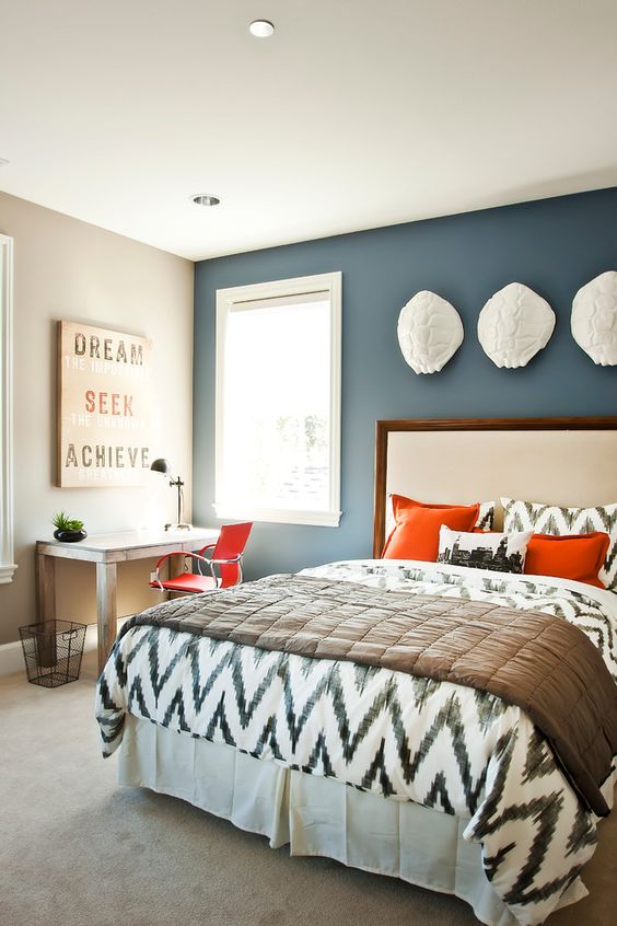 a guest bed and a home office are tied with the use of orange, which makes the space cool