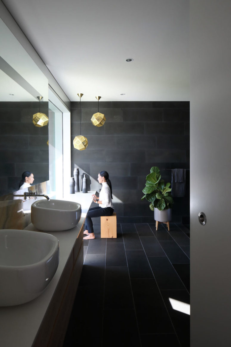 dark bathroom design The bathroom is clad with dark tiles, sculptural sinks and some wooden touches for a spa feel