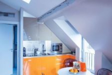 09 a minimalist kitchen nook with a skylight, bold orange cabinets and sheer black chairs