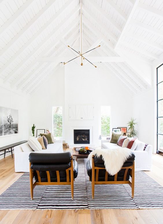 an airy pure white space with two white sofas and black leather chairs that contrast the whites