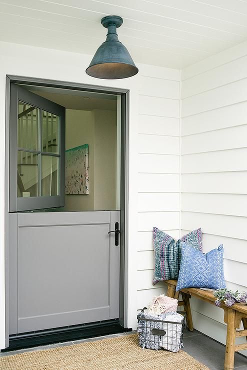 a cozy porch with a bench, a wire bakset and a grey Dutch door for a vintage feel