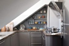 11 a small attic industrial kitchen with grey cabinets and stainless steel with a large skylight