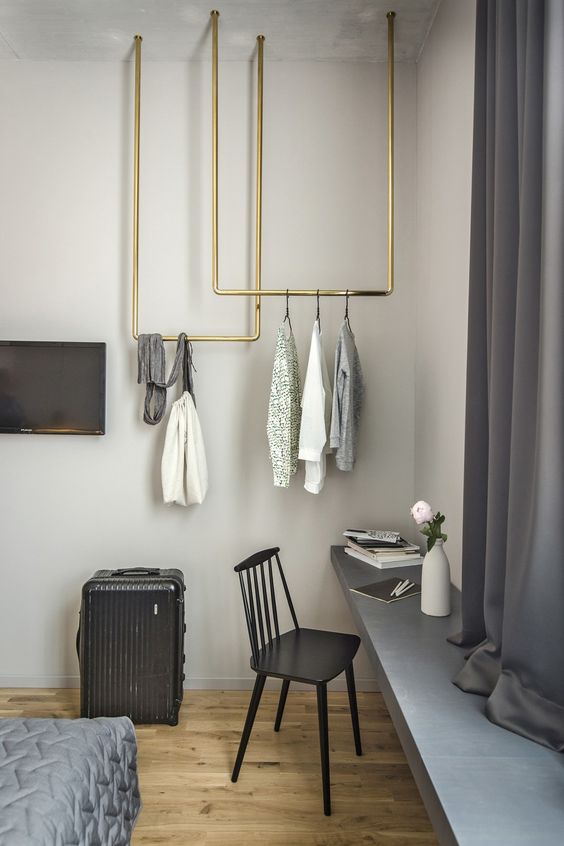 stylish brass pipe racks attached to the ceiling look super stylish and spruce up the grey space