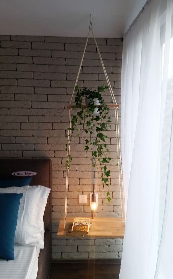 a hanging bedside table of two tiers, the first as a plant stand, the second as a nightstand