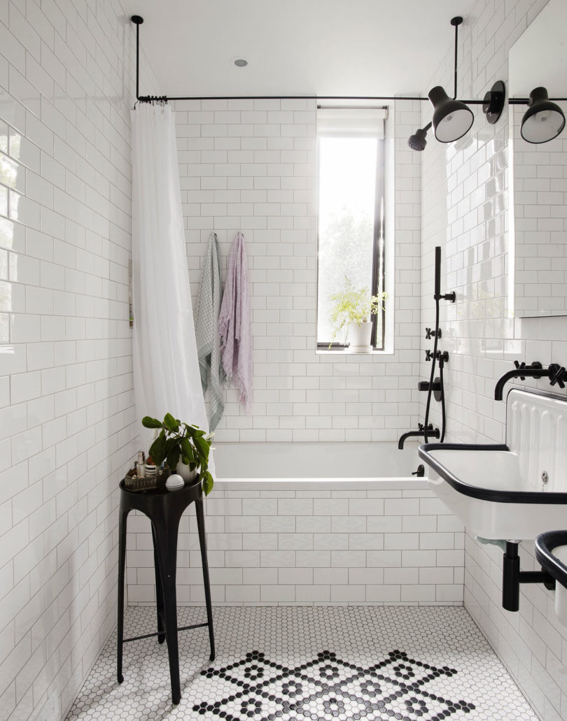 The bathroom is done with white tiles with black grout for a chic and otustanding look