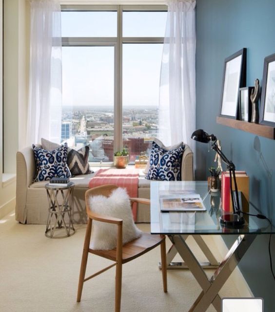 a guest bedroom with a stylish bed by the window and a glass and metal desk for working