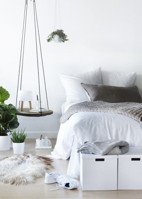 a serene bedroom with a wood slice hanging bedside table and a storage bench