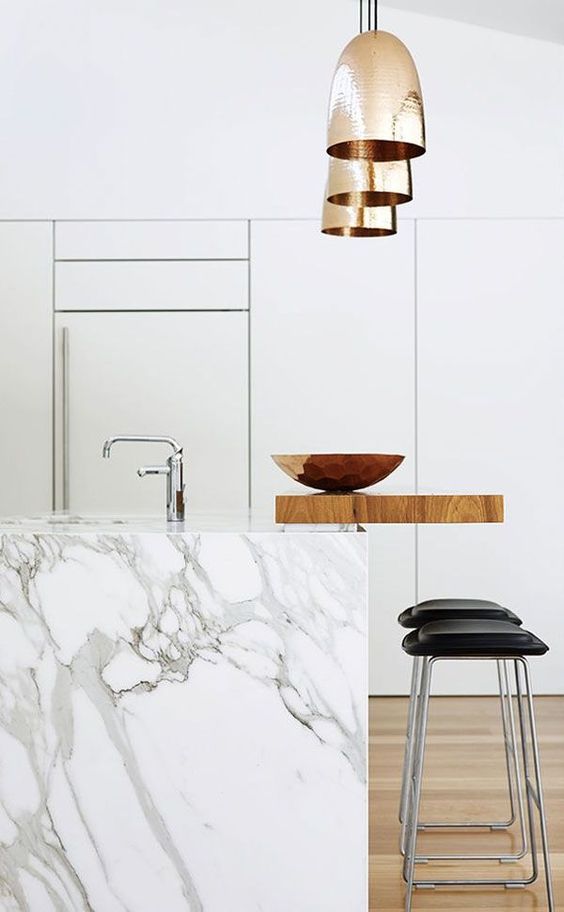 a kitchen island of white marble with an additional wooden countertop to use for having meals and drinks