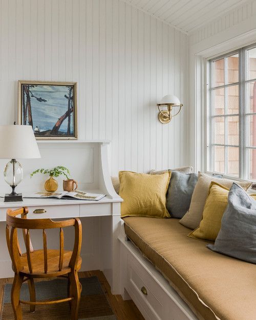a cozy guest bedroom with white shiplap on the walls and ceiling, a built-in bed with yellow bedding, a built-in desk, a stained chair and some decor