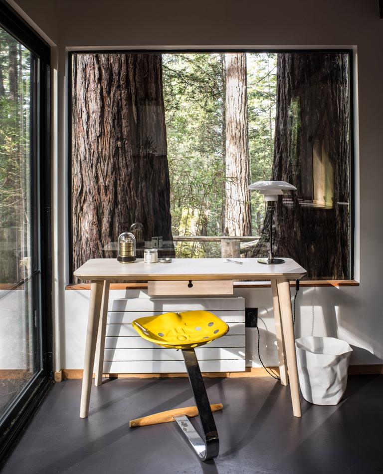 stylish mid century modern home office with a forest view The home office features a mid-century modern desk and a bright stool, there are openings outside everywhere