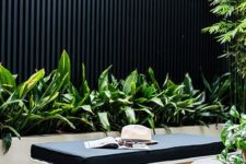 02 a black wooden plank fence is combined with a large planter with greenery for a lively feel