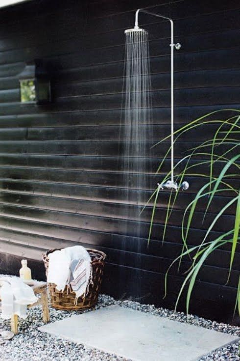 a bold contemporary and Scandinavian shower with a black wooden wall, pebbles and a stone tile