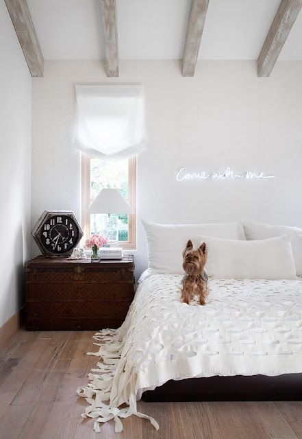 a neutral boho space spruced up with dark-stained furniture and a calligraphy neon light over the bed