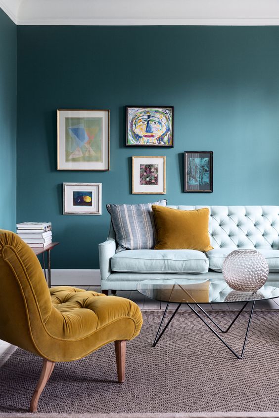this bold living room features an asymmetrical gallery wall and a chair in front of a sofa