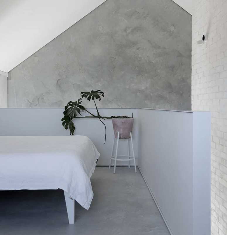 The master bedroom is done with concrete and brick walls, a lilac half wallm which adds color and a lilac planter