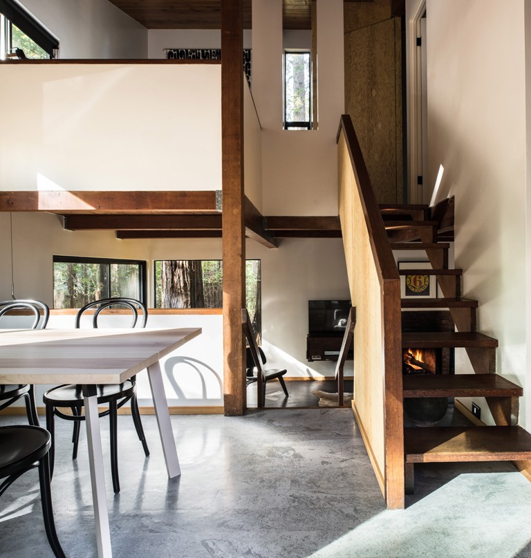 The dining space is done with a light colored table and black chairs, the living space is done with a fireplace downstairs The dining space is done with a light-colored table and black chairs, the living space is done with a fireplace downstairs