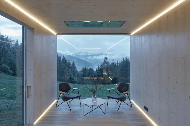 The interior is minimalist, everything is clad with light-colored wood, there are built-in lights and comfortable furniture
