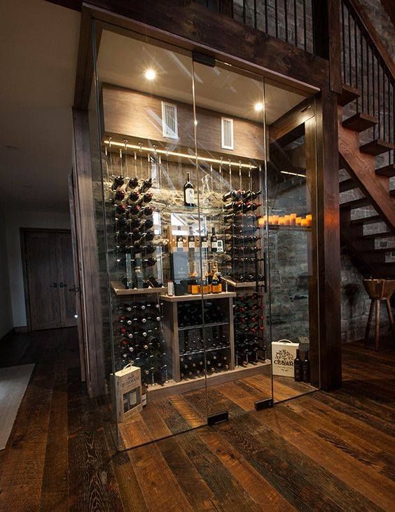 a gorgeous glass-enclosed wine cellar under the stairs with additional lights and candles