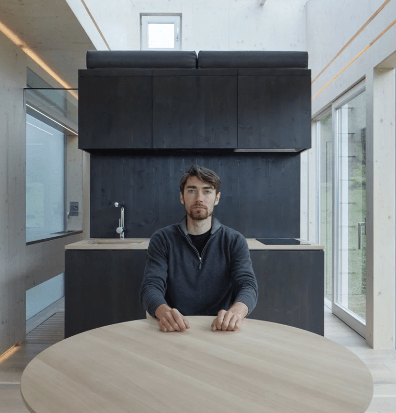 The kitchen is done with dark cabinets that feature a sleeping space on top and a round table