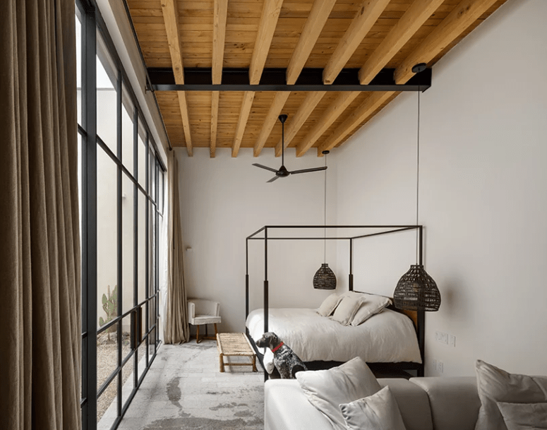 modern bedroom with concrete flooring The master bedroom is done with a glazed wall with doors, there are wooden beams, a concrete floor and comfy furniture