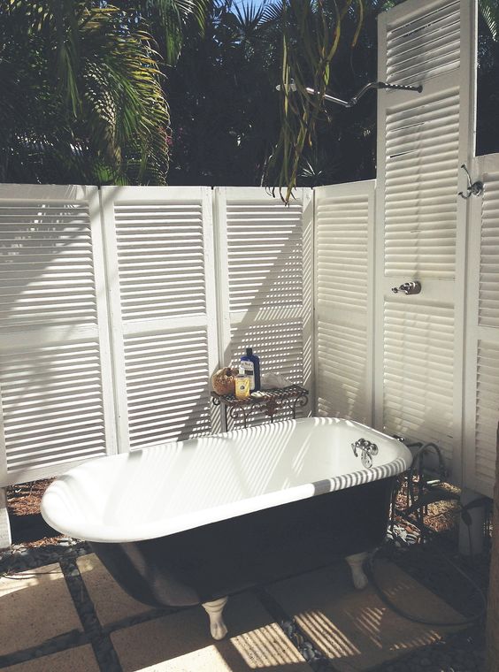 a modern space with a black bathtub, a coffee table and some shutters for keeping privacy