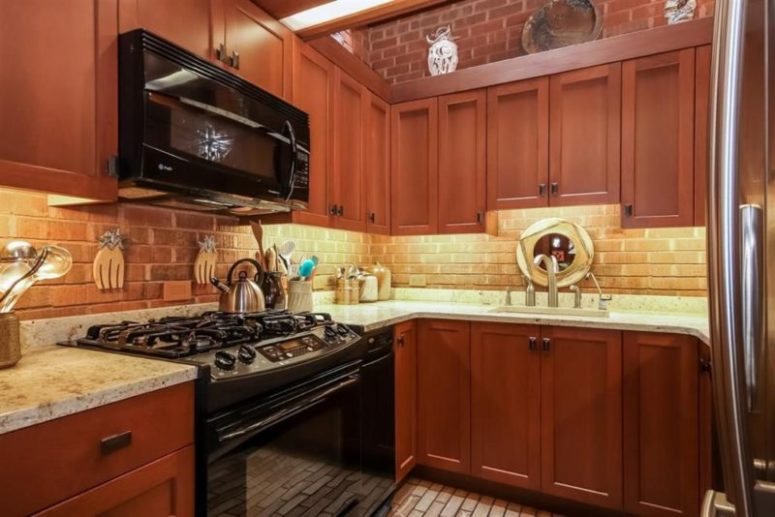 kitchen with marble countertops Red wood cabinets with marble countertops create a contrasting look and a brick backsplash adds to the space