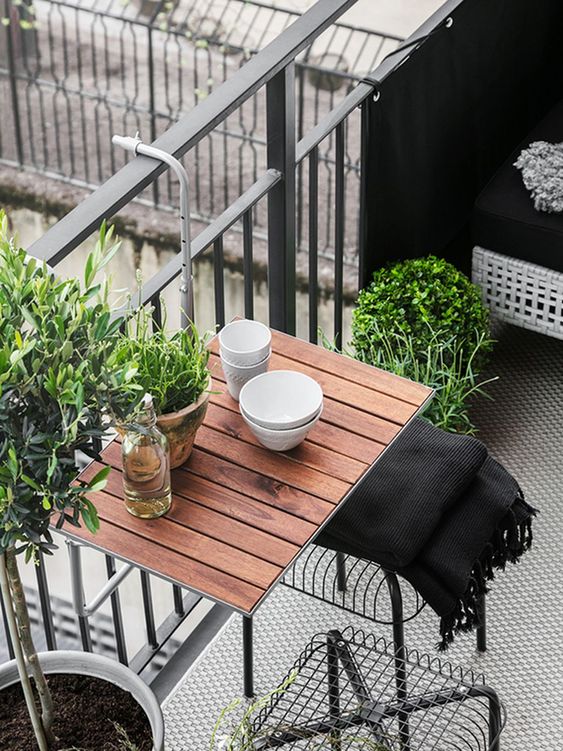 a hanging table, metal chairs and a wicker seat plus potted greenery for a lively modern look