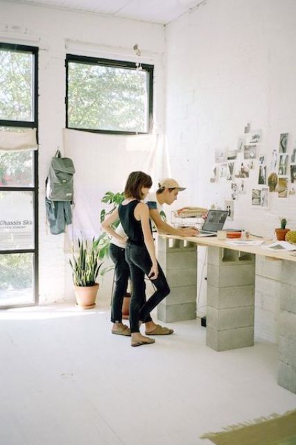 a large double stand desk built of cinder blocks and a wooden countertop for an industrial space