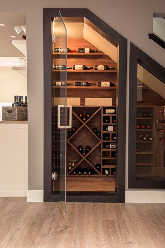 a small yet stylish wine cellar under the stairs with various plywood shelves for the bottles