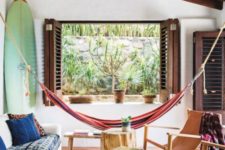 11 a tropical living room with a colorful striped hammock, a surf and dark stained shutters