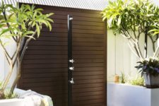 12 an outdoor contemporary shower with a dark stained wooden platform, potted trees around