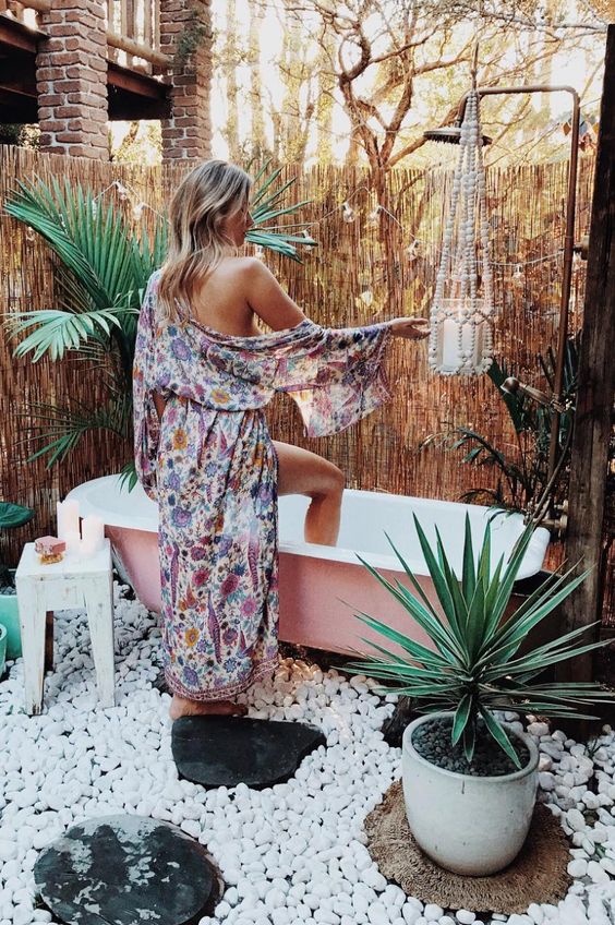 a gypsy-inspired outdoor space with a pink bathtub, potted plants and pebbles plus a wooden bead planter