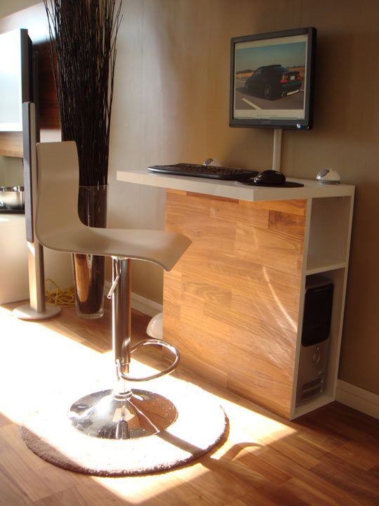 a tall and sleek stand desk work station with storage space inside and a large comfy stool