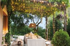 an outdoor dining space lit up with lots of lights and some candle lanterns