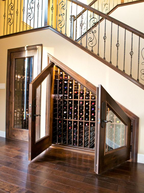 an under stairs wine storage space with lots  of shelves for bottles and glass doors