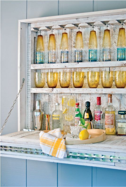 an outdoor foldable beachy bar of whitewashed wood with colorful glasses for a relaxed beach-inspired space