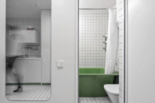 03 The bathroom is small but still features a comfy green bathtub and even soem shelves